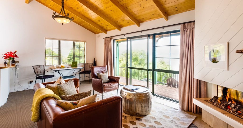 Luxurious Lake Cottages hotel room with panoramic water views, modern wooden furnishings, and floor-to-ceiling windows overlooking scenset landscape.