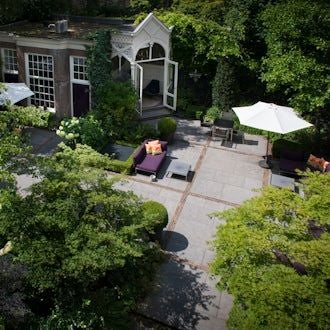 Historic canal-side boutique hotel with elegant Dutch architecture, large windows, and warm lighting reflecting on tranquil water in Amsterdam's scenic urban landscape