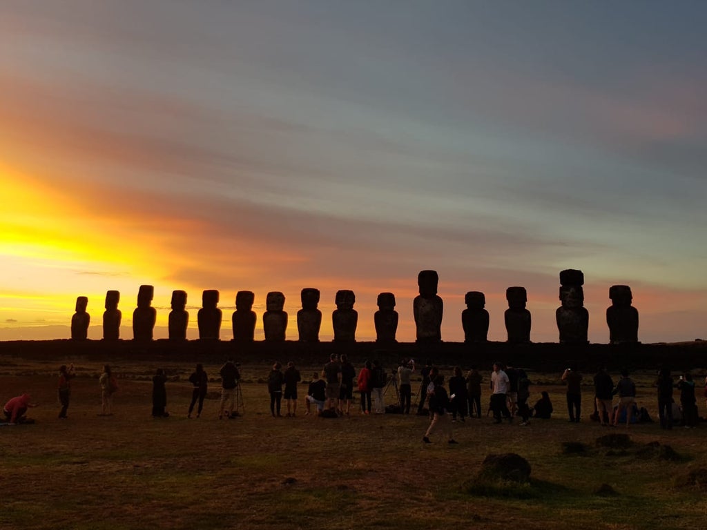 Luxurious oceanfront resort with curved stone architecture, infinity pool overlooking Easter Island's dramatic coastline and horizon