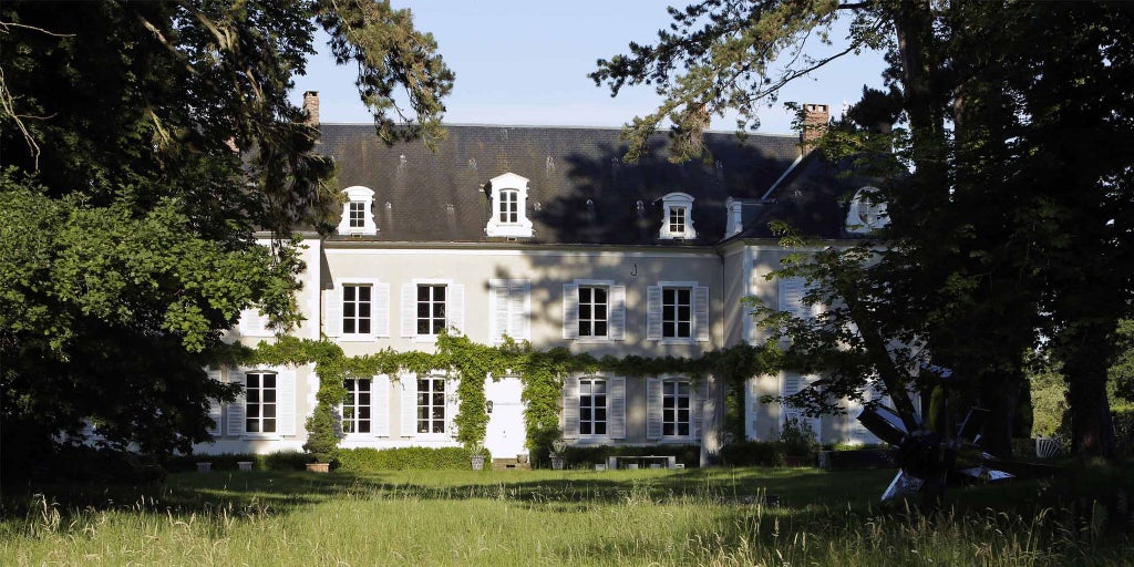 Elegant 18th-century stone château with manicured gardens, surrounded by lush French countryside, showcasing refined luxury and architectural grandeur