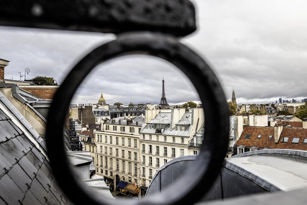 Elegant Parisian suite with plush white bedding, modern minimalist decor, soft neutral tones, and expansive city view through large windows at scenset Hotel Montalembert