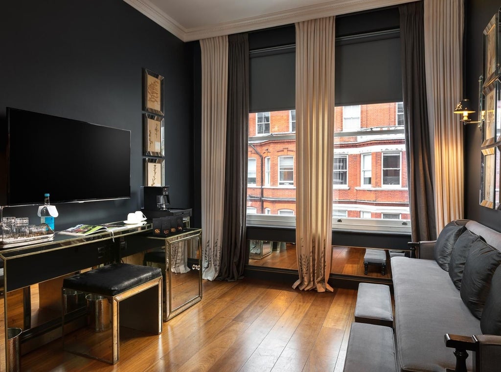 Elegant executive suite with plush king bed, modern grey upholstered headboard, soft ambient lighting, and panoramic city skyline view in a chic United Kingdom hotel room