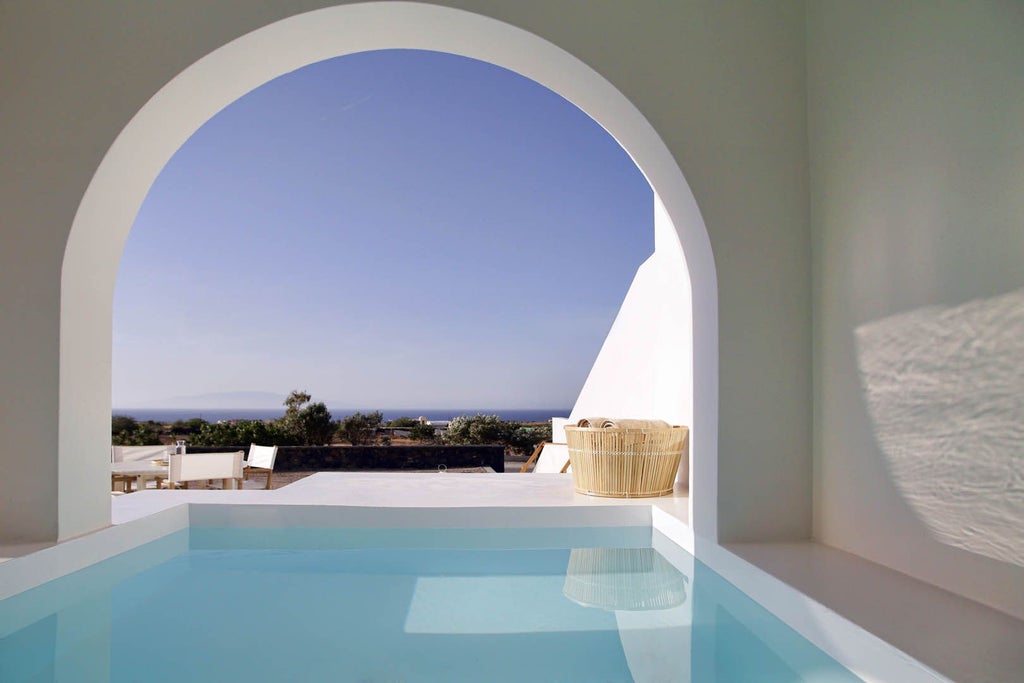 Luxurious white-washed Greek villa with blue-domed roofs overlooking the Aegean Sea, nestled in the picturesque landscape of a traditional Cycladic village in Greece.