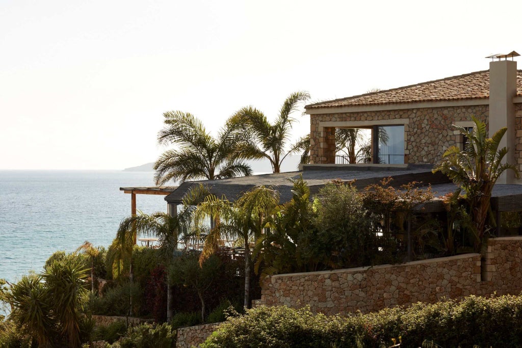 Luxurious white minimalist Greek hotel overlooking azure Kefalonian coastline with infinity pool, elegant loungers, and stunning Ionian Sea panorama