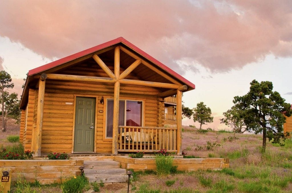 Rustic luxury cabin interior with wooden beams, plush bedding, large windows overlooking scenic mountain landscape at scenic Mountain Ranch retreat