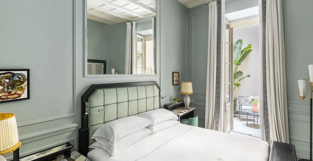 Elegant Florentine hotel room with ornate gold-framed artwork, rich fabric headboard, crystal chandelier and classic Italian furnishings