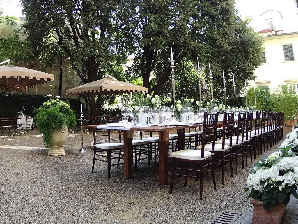 Elegant 16th-century Palazzo di Camugliano in Tuscany, with rich terracotta facade, ornate windows, and lush Renaissance garden courtyard.