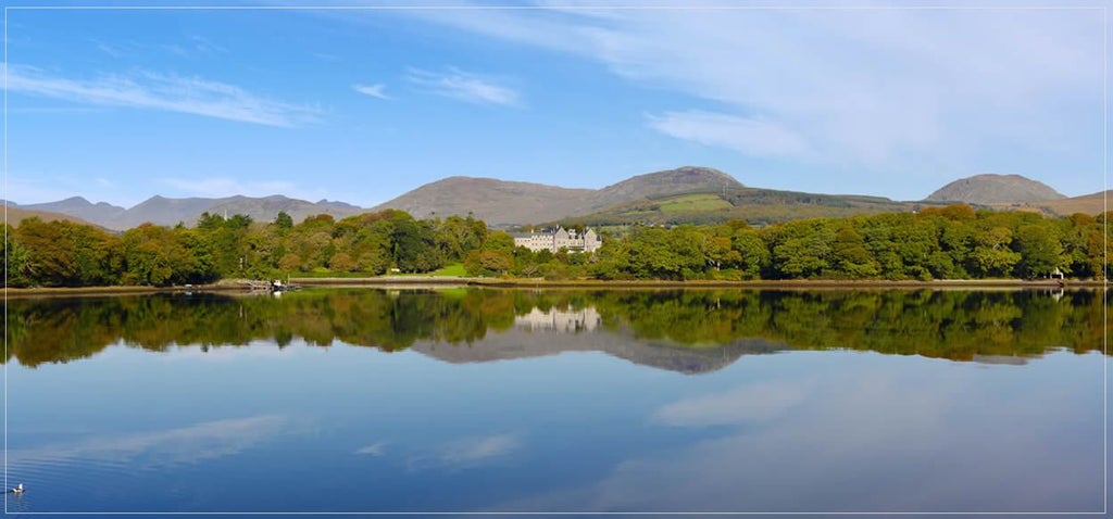 Luxurious stone-built Hotel Kenmare nestled in lush Irish countryside, featuring elegant architecture with stone walls and traditional windows surrounded by green landscape