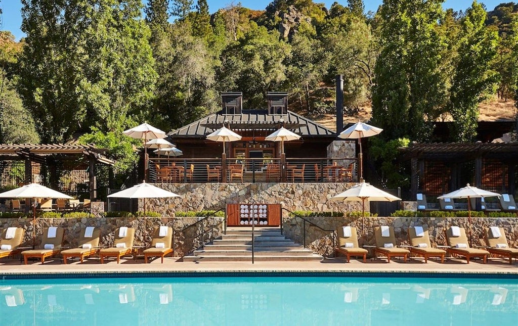 Luxurious wooden lodge nestled among tall trees at Calistoga Ranch, featuring a natural stone patio and elegant outdoor furniture