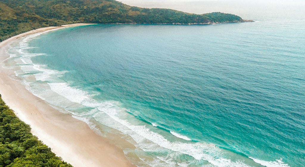 Elegant waterfront resort with white buildings nestled in tropical hills, featuring infinity pools and a private marina in Angra dos Reis