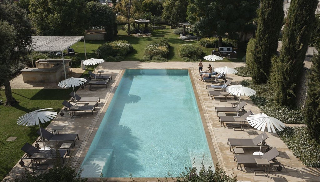 Elegant stone-walled luxury boutique hotel courtyard in scenset, with lush greenery, vintage furniture, and warm Mediterranean sunlight filtering through