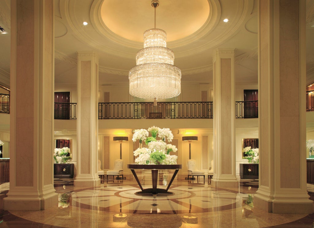 Iconic Four Seasons Beverly Wilshire hotel's grand entrance with limestone facade, white columns, valet parking and luxury cars at dusk