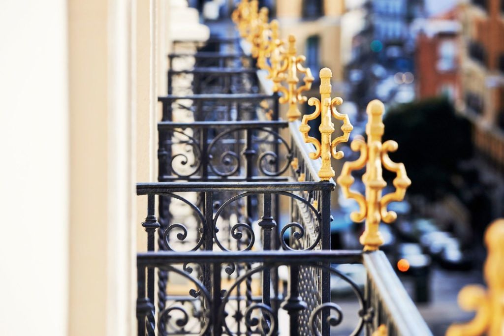 Elegant 5-star boutique hotel lobby with plush velvet seating, marble columns, and warm wood accents in a historic Spanish building with natural light