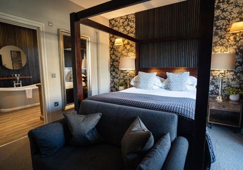 Elegant UK boutique hotel room at Scenset with plush bedding, sophisticated neutral decor, and large windows overlooking serene countryside landscape