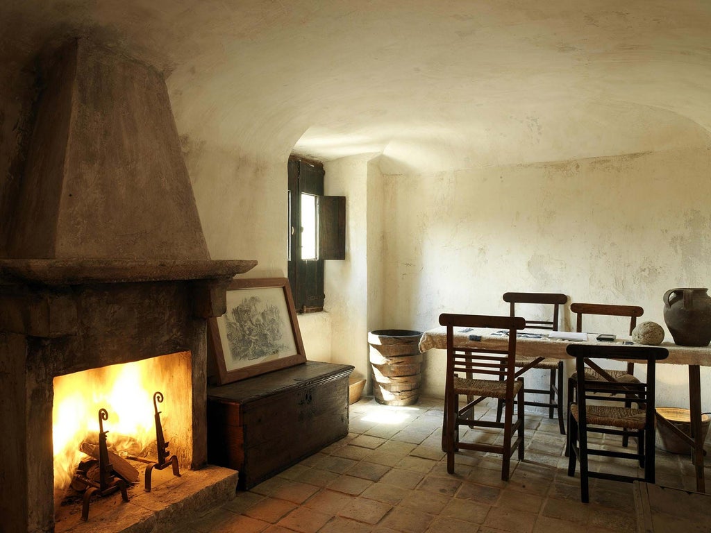 Rustic Italian hotel room with stone walls, antique wooden furniture, and panoramic view of medieval bell tower, bathed in soft golden light