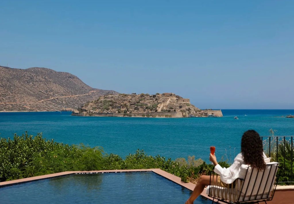 Luxurious beachfront resort with white domed architecture, azure Aegean waters, and private infinity pools overlooking scenic Cretan coastline at Domes of Elounda