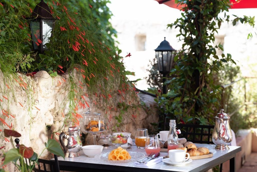 Elegant stone facade of boutique Hotel Le Saint Paul in charming French village, featuring classic architectural details and warm golden sunlight.