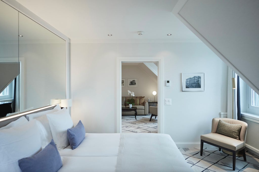 Elegant lifestyle suite with panoramic river and plaza views, featuring modern decor, plush seating, and warm ambient lighting in Zurich