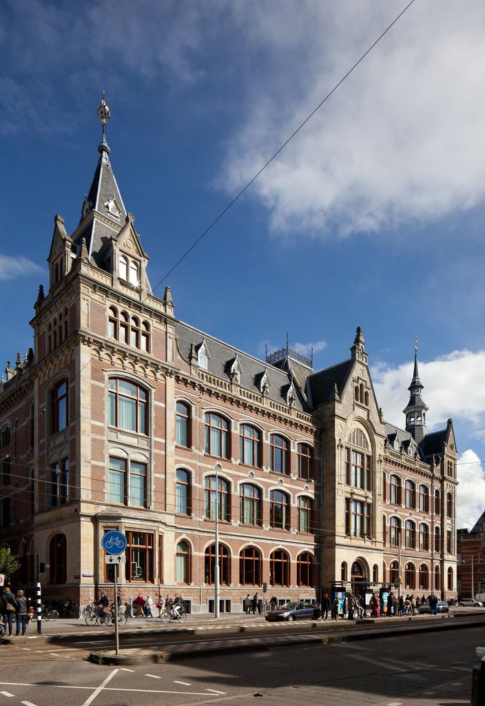 Elegant luxurious glass-fronted hotel with modern architectural design, nestled in historic Amsterdam with sleek contemporary interiors visible