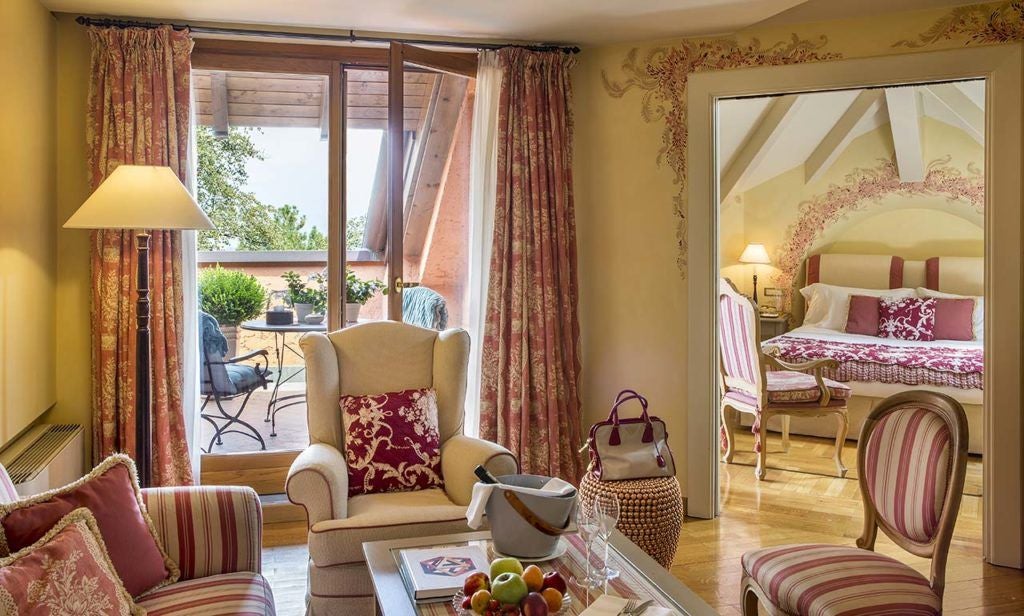 Elegant superior room at L'Albereta in Italy, featuring plush white bedding, soft neutral tones, and large windows overlooking scenic countryside landscape