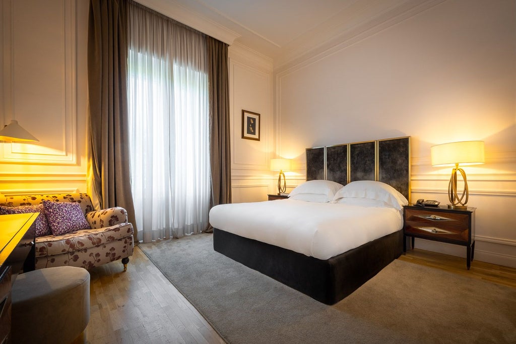 Elegant double deluxe hotel room at Palazzo Dama in Italy, featuring plush white bedding, modern marble accents, and soft neutral color palette.