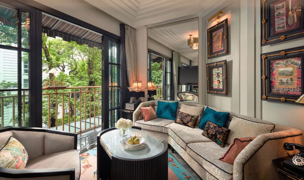 Opulent hotel suite with French colonial decor, featuring crystal chandeliers, ornate gold mirrors, and plush king bed with silk linens