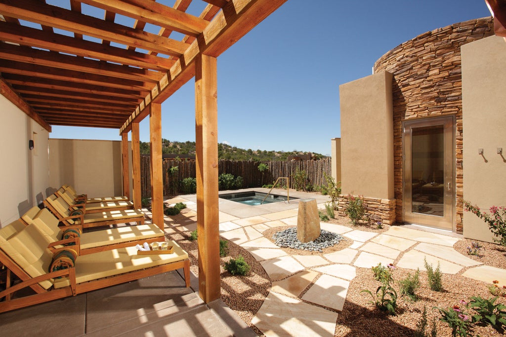 Adobe-style luxury resort with earth-toned stucco walls, terracotta roof tiles, and native gardens set against Santa Fe's desert landscape