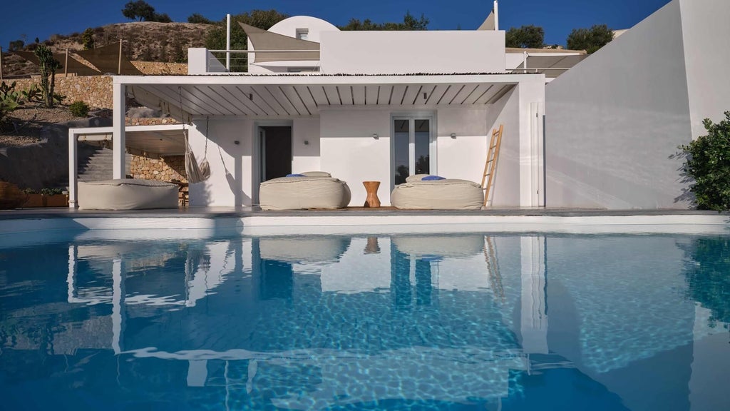 Luxurious white-washed Santorini suite with minimalist design, featuring a private balcony overlooking azure Aegean waters and volcanic landscape