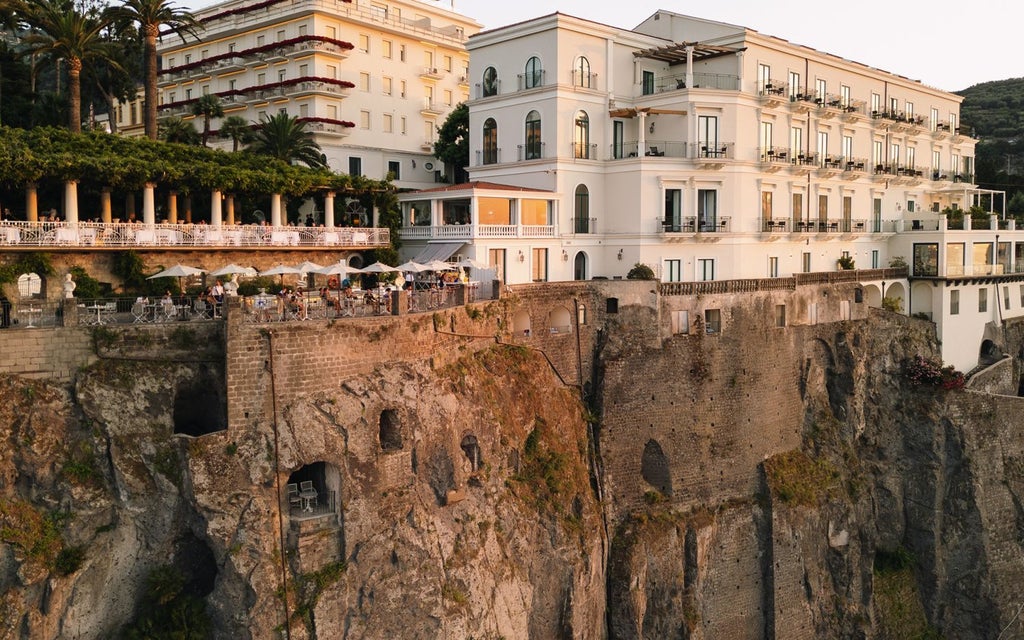 Luxurious Bellevue Syrene hotel overlooking azure Mediterranean waters, with elegant Italian architecture and sun-drenched limestone cliffs of Sorrento coastline