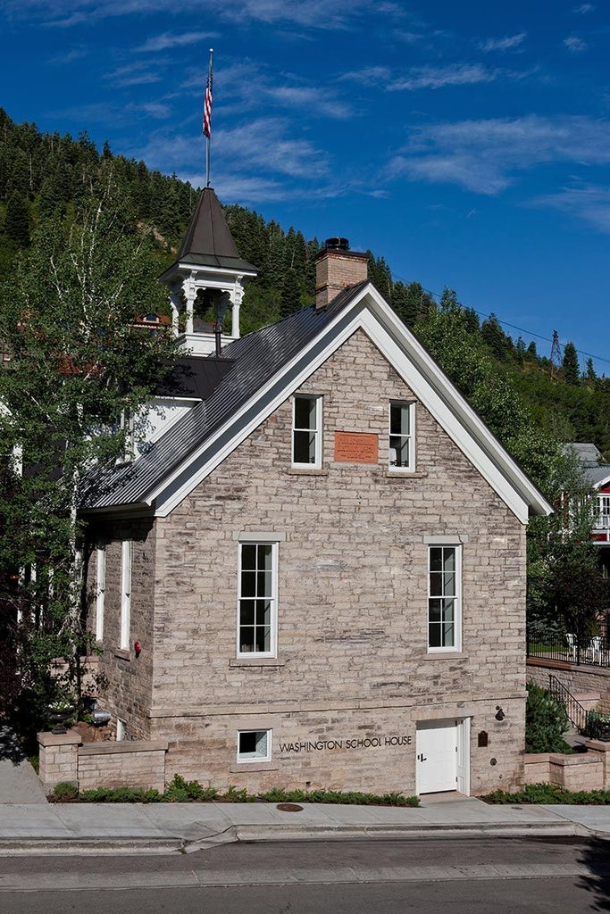 Elegant boutique hotel exterior with white historic building, arched windows, and manicured garden, showcasing luxurious architectural charm in scenic location