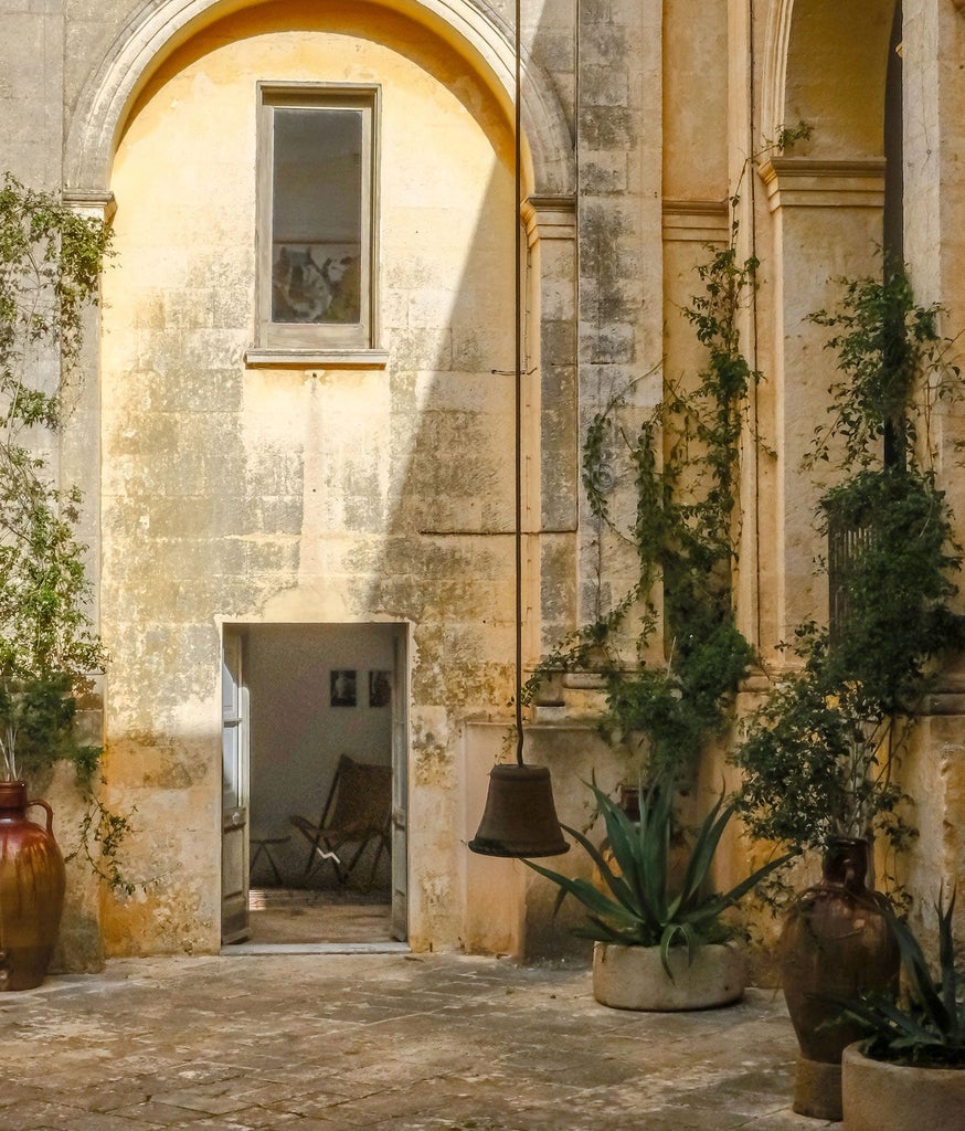 Elegant Italian hotel suite with high ceilings, ornate plaster details, antique furnishings, and soft natural light illuminating restored historical architectural elements