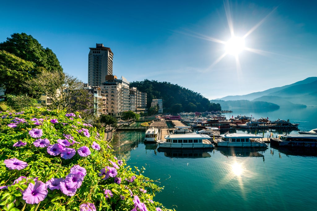 Scenic Taiwan landscape with Sun Moon Lake's azure waters, lush mountains, traditional pagoda, and a luxurious tour boat gliding across serene waters at golden hour.