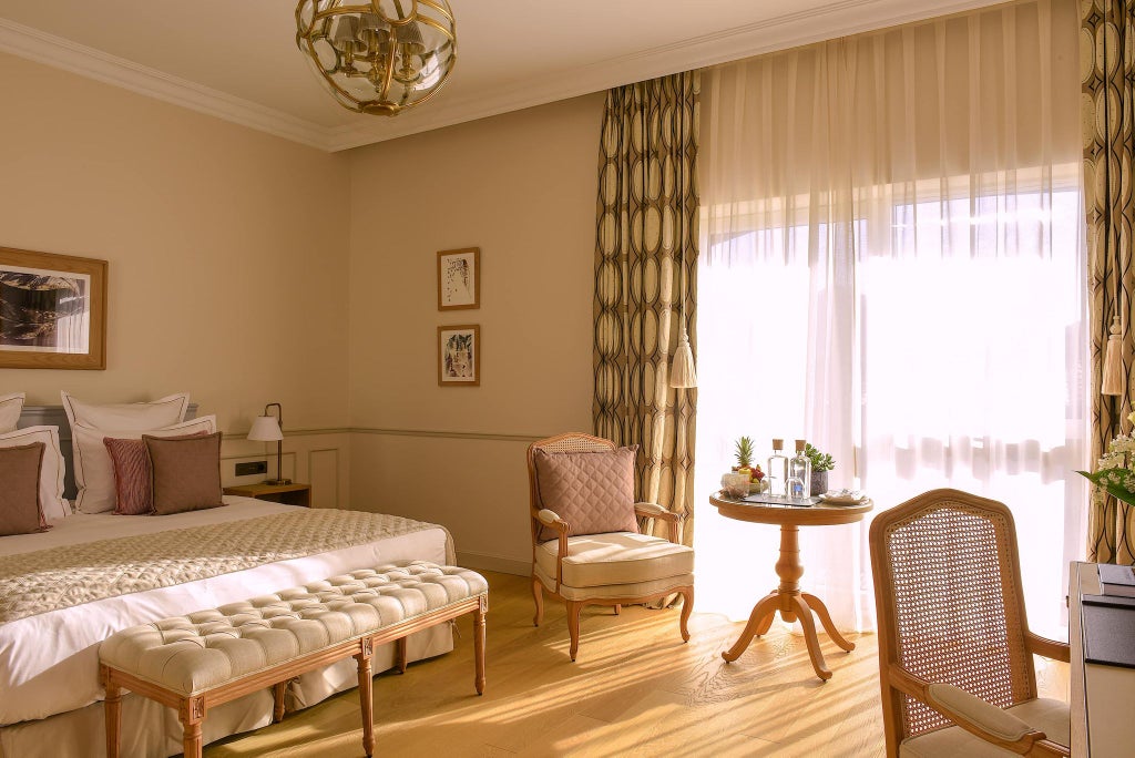 Elegant hotel room with soft neutral tones, plush white bedding, modern wooden furniture, and large windows overlooking scenic French countryside at Hôtel Chais Monnet & Spa