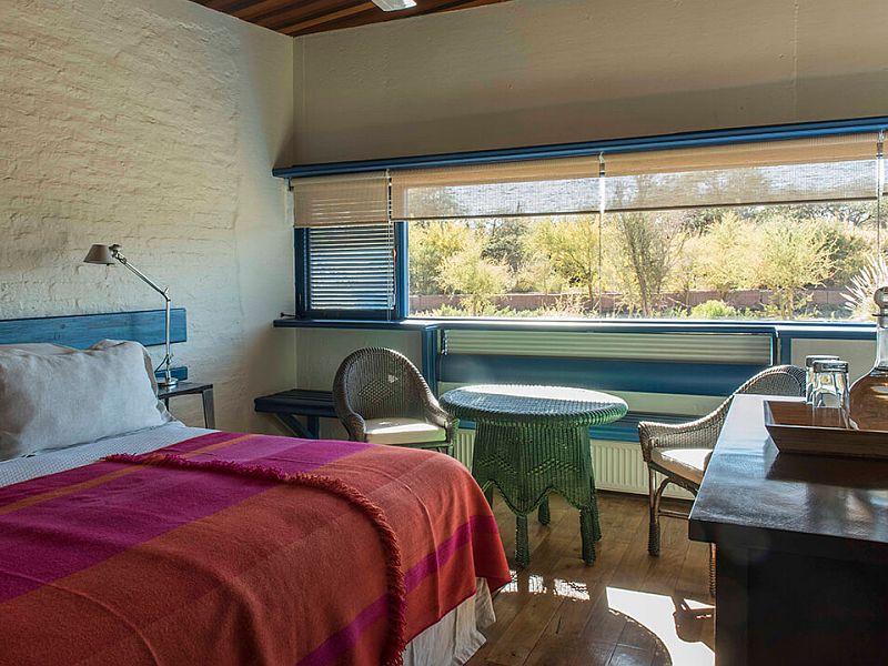 Upscale desert lodge with adobe-style architecture, wooden terrace, and Andes mountains backdrop at sunset in Atacama Desert, Chile