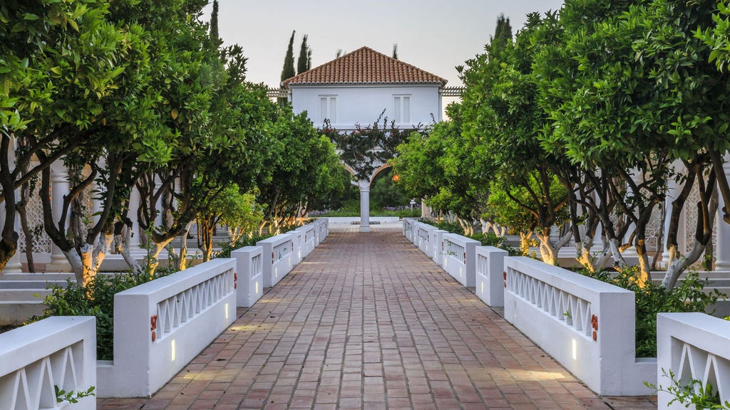 Elegant luxury hotel nestled in Portuguese hillside with white stone facade, arched windows and lush Mediterranean gardens