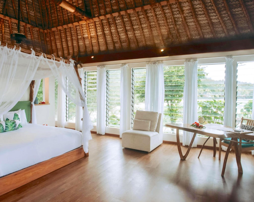 Luxurious Vonu Point Villa with panoramic ocean views, featuring elegant wooden interiors, plush king bed, and direct access to pristine white sand beach in Fiji