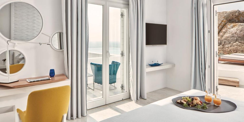 Luxurious white minimalist suite with panoramic Aegean Sea view, featuring elegant design, infinity pool, and stunning Mykonos sunset horizon backdrop