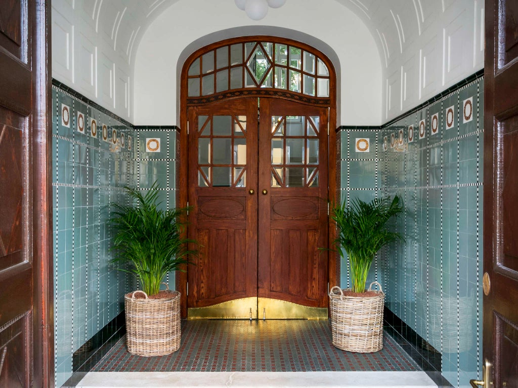 Elegant marble hotel entrance with classic columns, brass-framed glass doors and ornate lighting fixtures in Split's historic center