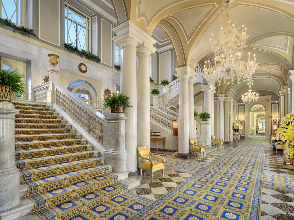 Renaissance-style Italian villa with ornate terraced gardens overlooking Lake Como, featuring grand fountains and manicured hedges at sunset