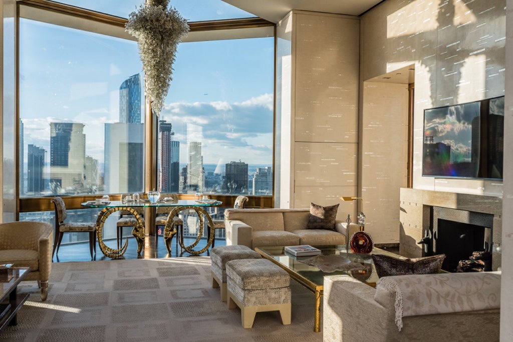 Towering art deco-style luxury hotel with limestone facade, golden revolving doors, and illuminated entrance canopy in Midtown Manhattan