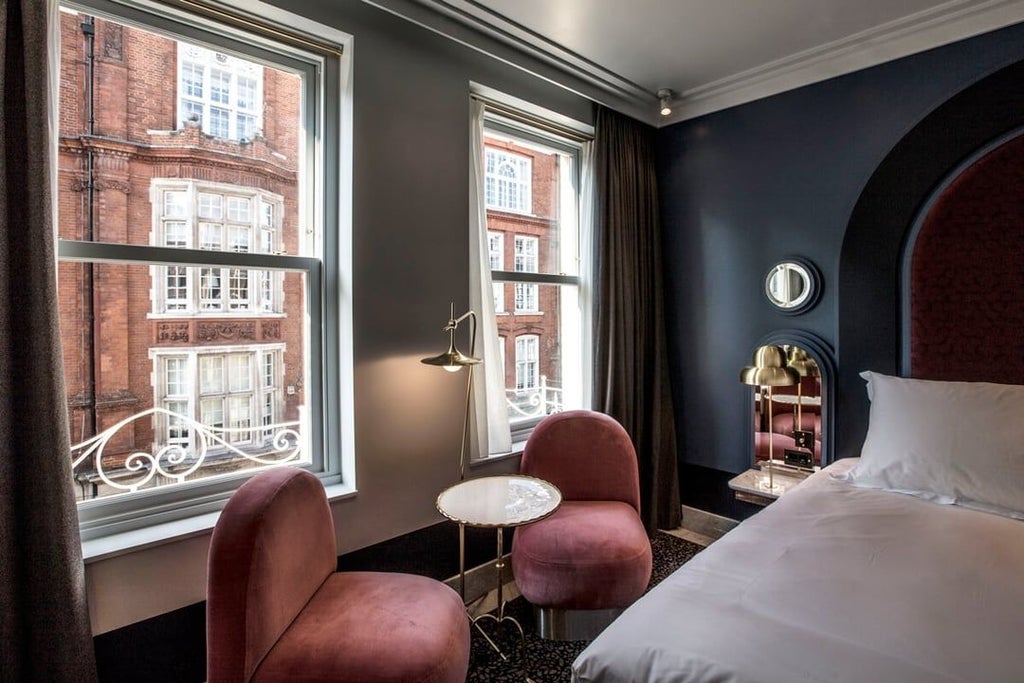 Sophisticated superior room with plush white bedding, elegant gray headboard, and large window overlooking Covent Garden's charming urban landscape in a luxe UK hotel