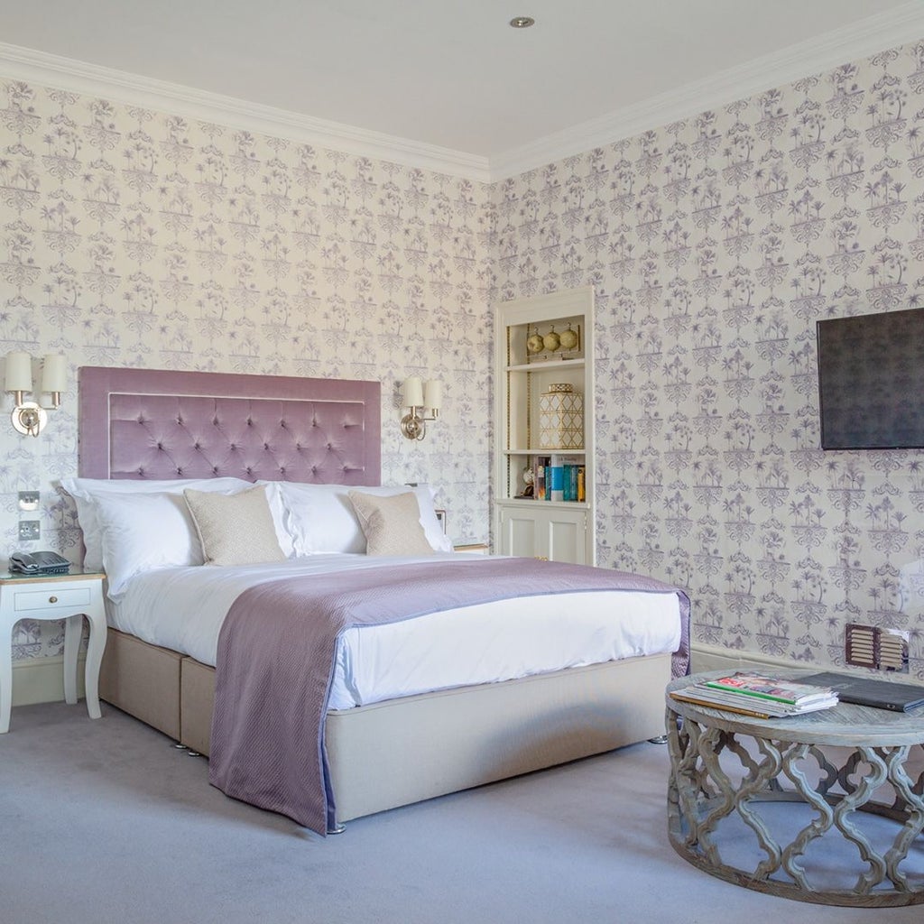 Elegant superior hotel room with plush white bedding, sophisticated grey accent wall, modern minimalist decor, and soft ambient lighting in a luxurious UK boutique setting