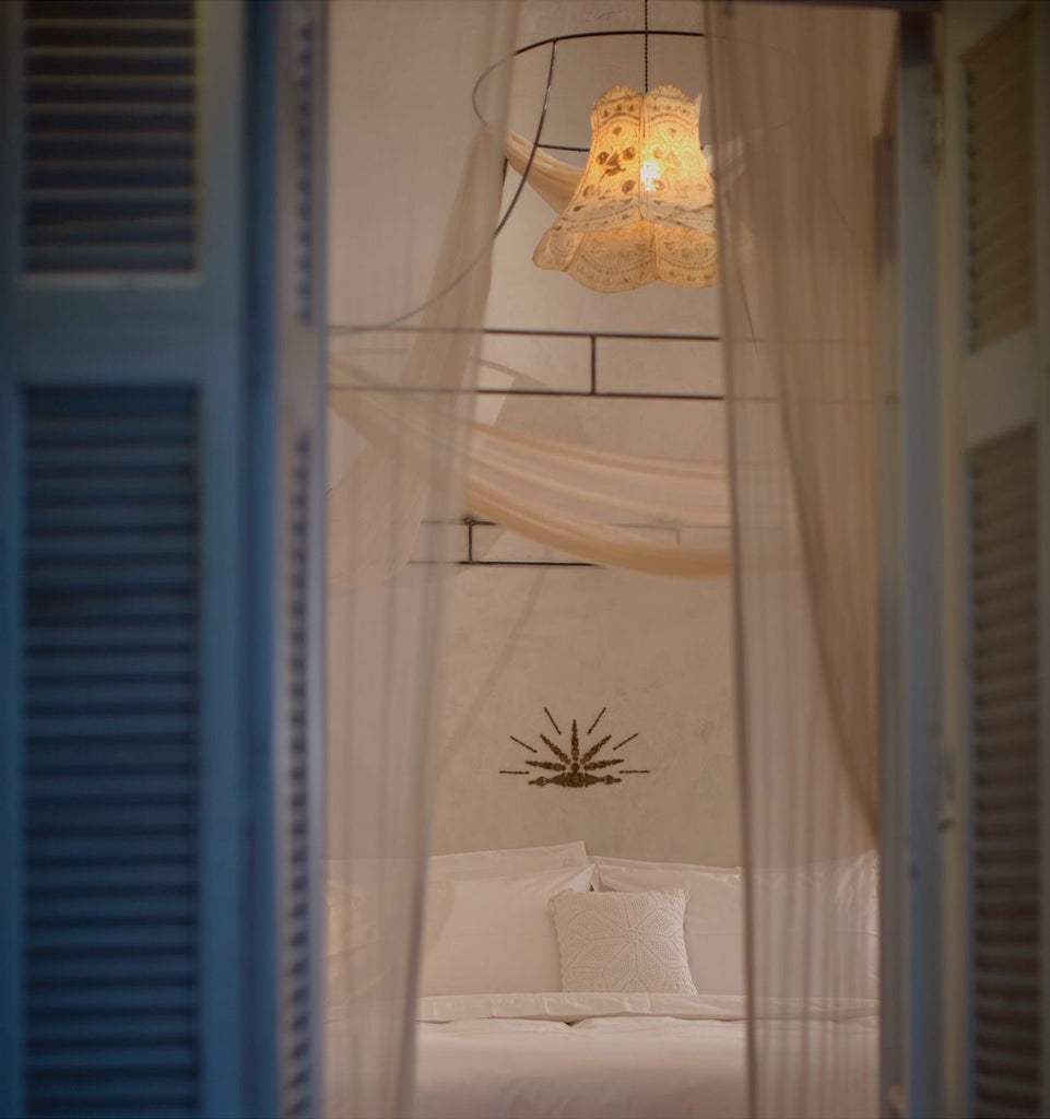 Elegant boutique hotel room with soft dusty rose bedding, marble accents, minimalist design, and panoramic Athens cityscape through large windows