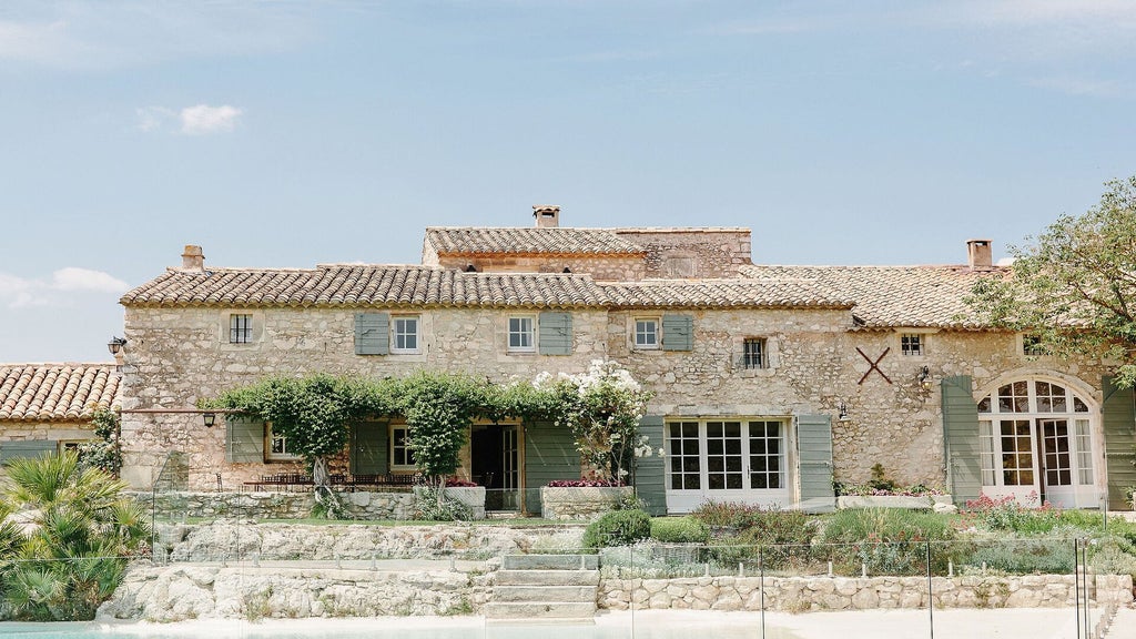 Elegant French countryside hotel with rose gardens, stone facade, and manicured lavender fields under soft golden afternoon sunlight