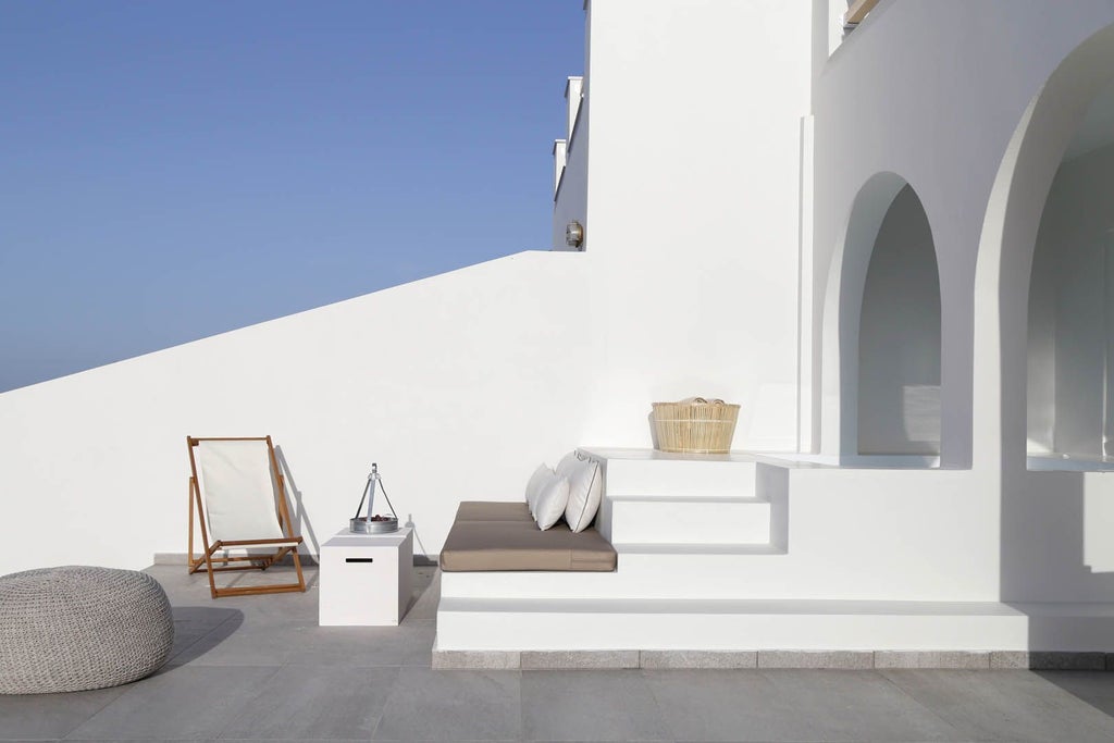 Luxurious whitewashed Greek villa with blue-domed roofs nestled on a cliff overlooking the stunning Aegean Sea in Santorini's iconic landscape