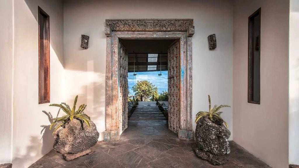 Luxurious safari-style eco-lodge nestled in Galapagos highlands, with elegant teak deck overlooking lush volcanic landscape and distant Pacific Ocean.