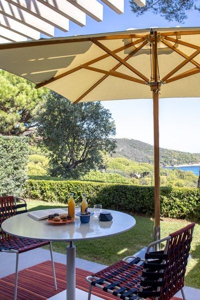 Elegant deluxe hotel room with panoramic sea view, minimal design, crisp white linens, and lush garden terrace at La Réserve Ramatuelle luxury resort, France