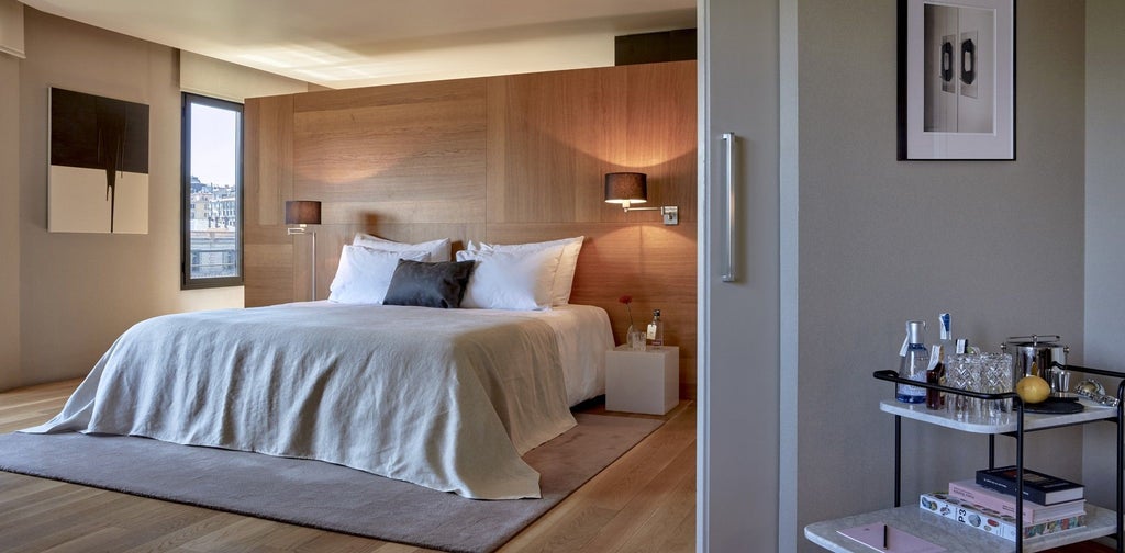 Luxurious modern suite with sleek design, city skyline view, minimalist furniture, warm wood tones, and contemporary Spanish architectural elegance