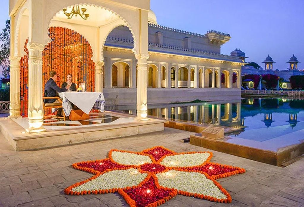 Ornate luxury hotel with domed architecture reflects in serene pool at sunset, surrounded by manicured gardens and archways