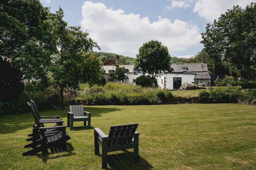 Rustic stone farmhouse with elegant slate roof, surrounded by lush countryside, showcasing traditional UK rural architecture and tranquil pastoral setting